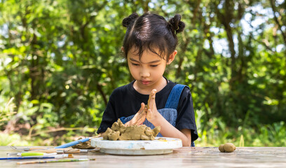 Young Asian girl working with clay in outdoor pottery workshop