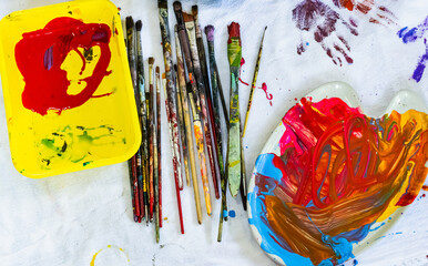 Dirty used artist paintbrushes and color paint palette in art studio