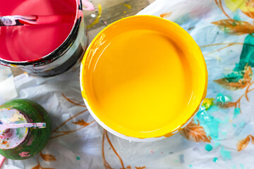 Top view opened yellow and red painting tins in art studio