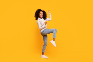 Fototapeta na wymiar Joyful african american woman dancing on yellow background