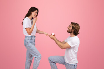 Happy young caucasian man on knee give ring box to surprised woman