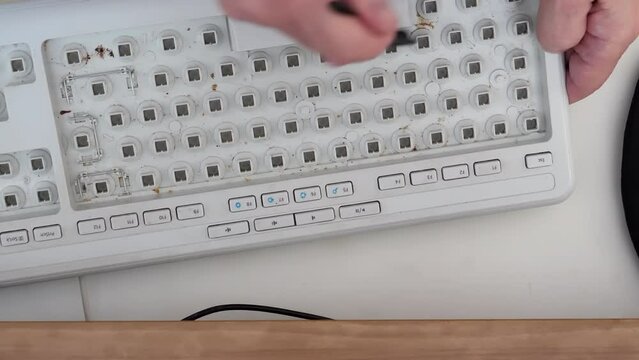 Cleaning brushing computer keyboard with brush after keycaps removed.
