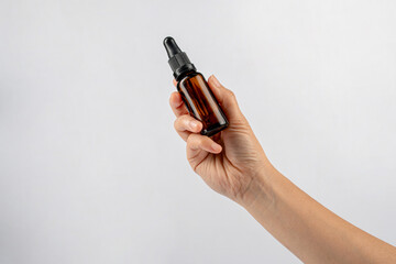Cosmetic bottles made of dark amber glass in hand on white background