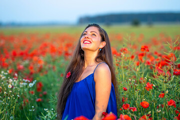 portrait of elegant young woman in poppy field in evening sunlight