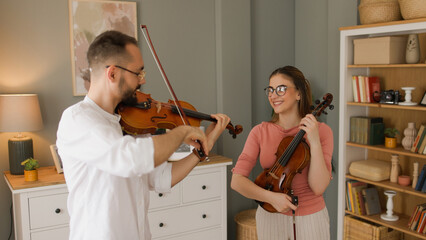 Male violin teacher demonstrating teenage girl how to play a piece © Stockphotodirectors