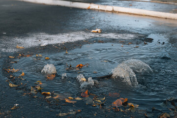 Accident of water supply, sewage. Water fountain pours out from under the road sewer. Breakthrough sewerage system. Water flows on the road from the sewer hatch