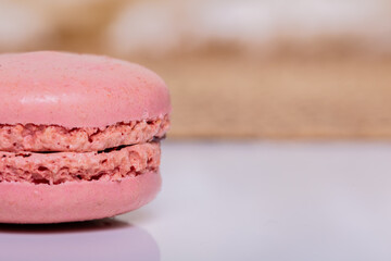Delicate pink macaron cookie on a pristine white table up close. Perfect for bakery banners and sweet treat promotions.