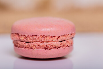 Delicate pink macaron cookie rests on a pristine white table, inviting a sweet indulgence. Perfect for bakery banners and confectionery ads. 