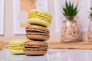 An enchanting display of vibrant macarons, meticulously stacked in a delightful array on a crisp white tabletop, harmonizing with the eclectic boho ambiance that adorns the background