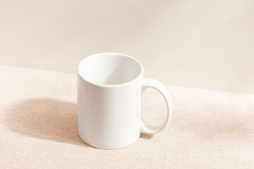 Obraz na płótnie Canvas White mug isolated on wood background. Drinking water. White mug. Beverage. Fabric surface. Simplicity. Minimalist object. Space for text. Mockup. Ceramic. Cup of coffee. Morning time.