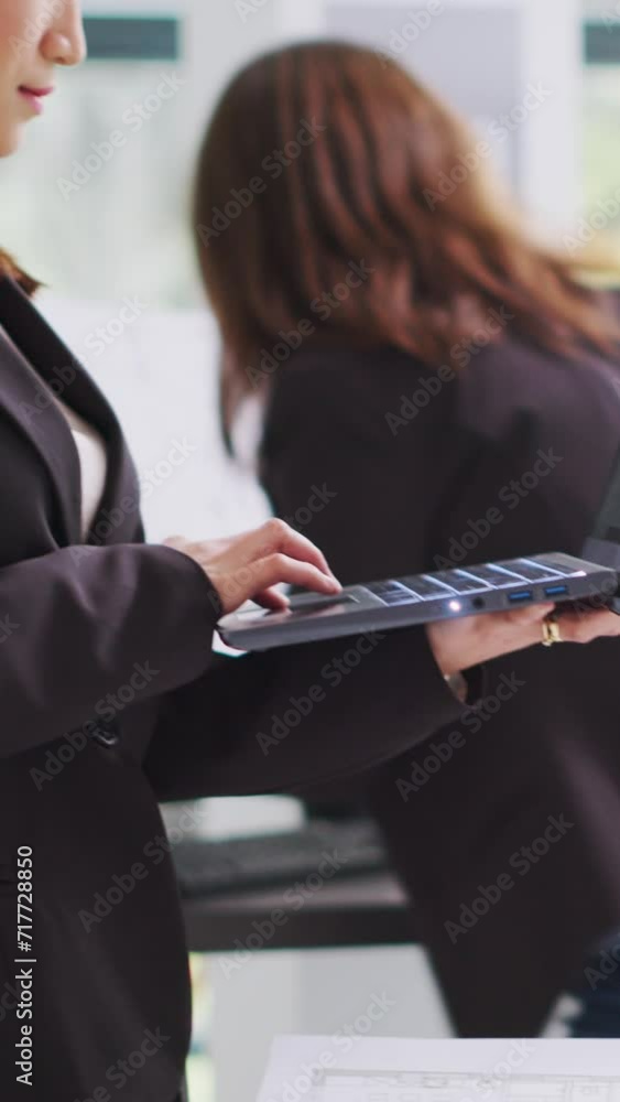 Poster vertical video architect takes notes on laptop for development plan, studying 3d building model on d