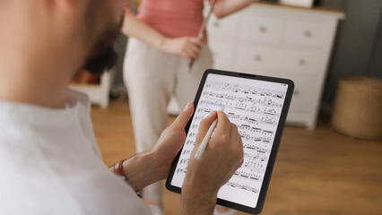 Male music teacher giving private violin lessons to a teenage girl using digital tablet