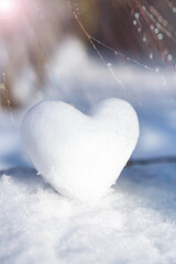 A snowy, tender heart against a winter background with beautiful bokeh.
