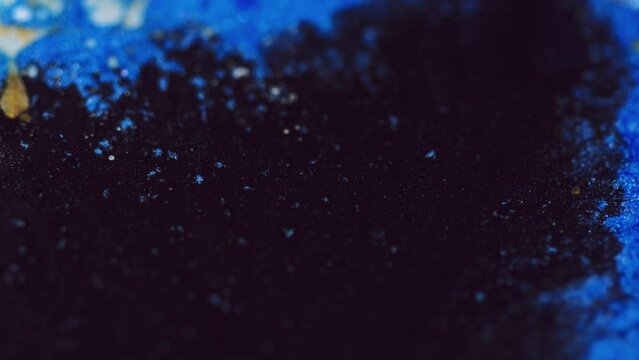 Glitter particles. Paint water flow. Defocused blue black golden color shimmering dust texture ink wave motion abstract art background.