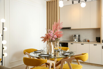 Dining table in the kitchen with pink flowers bouquet in the vase	