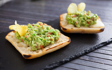 Toasted slices of square bread with warm cheese and homemade guacamole on plate for healthy breakfast