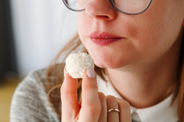 Close up of woman's mouth eating sweet candy with coconut, low calories food for people on a diet, special menu for losing weight - obrazy, fototapety, plakaty