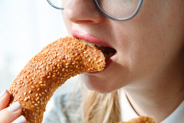 Close up of woman's mouth eating bun, biting bread with hanger, unhealthy snack with carbohydrate....