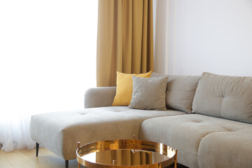 Grey comfortable sofa with mustard yellow cushion, curtains and coffee table, modern living...