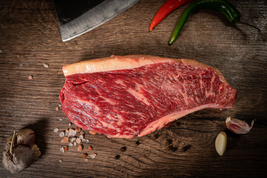 Raw hanging tender or onglet steak of beef on wooden Board with rosemary and thyme on wooden background