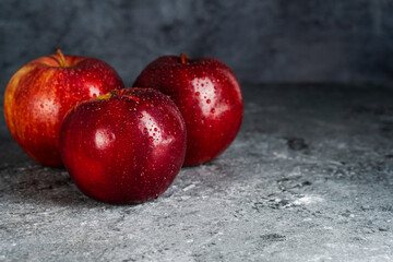 Wet and juicy fresh red apples with water drops on dark background with copy space. Selective focus