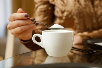 Woman adding sugar to hot drink	