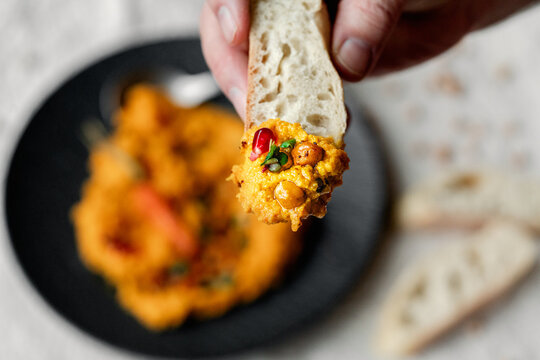 M&ouml;hren Hummus auf dunklem Teller mit Kichererbsen und ger&ouml;steter M&ouml;hre als Garnitur Leinentuch im Hintergrund