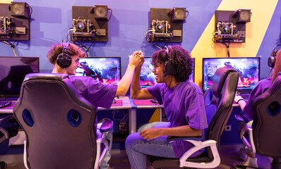 multiracial friends sand young gamers high-fiving hands celebrating victory in their online game