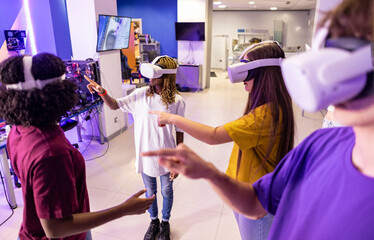 group of millennial teenagers playing in cyberspace moving their arms with their virtual reality...