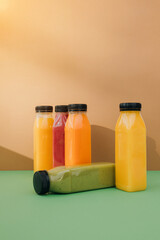Fruit and vegetable smoothies in transparent plastic bottles. Red, green, orange smoothies on a brown-green background. The concept of healthy eating. Front view