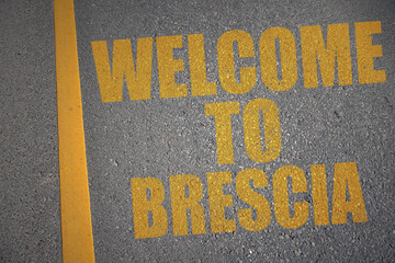 asphalt road with text welcome to Brescia near yellow line.