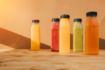 Fruit and vegetable smoothies in transparent plastic bottles. Red, green, orange smoothies on a wooden table. The concept of healthy eating. Front view