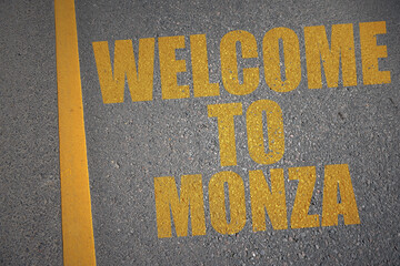 asphalt road with text welcome to Monza near yellow line.