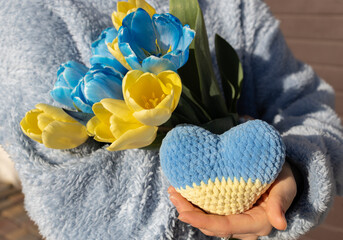 in women's hands there is a bouquet of tulips and a yellow and blue heart. a feeling of love for the homeland Ukraine. concept of revival, faith in victory. Independence Day. Mothers Day