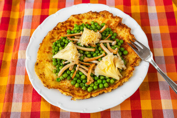 Egg omelette, pea, shimeji and cheese on white plate.
