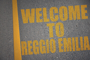 asphalt road with text welcome to Reggio Emilia near yellow line.