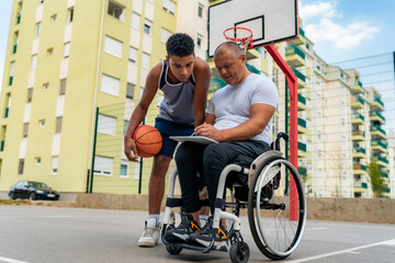 Fototapeta na wymiar The coach in the wheelchair shows the young black man the statistics from the previous game before they start training