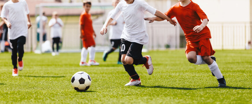 Children play soccer match. Anonymous football players kicking a ball. Two soccer teams compete in a duel during a school tournament game