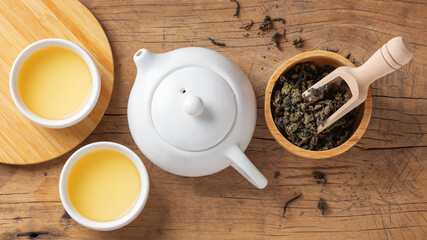 Fototapeta na wymiar Tea set with teapot and tea leaves in bowl on wooden table