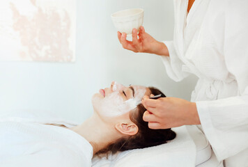 Obraz na płótnie Canvas Beautiful relaxed woman having clay face mask in spa salon
