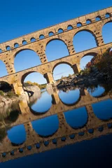 Photo sur Plexiglas Pont du Gard The Pont du Gard, vertical photography tilted over blue sky. Ancient Roman aqueduct bridge. Photography taken in Provence, southern France