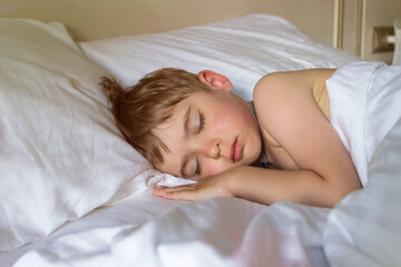 Defocused adorable little toddler boy sleeping in white bed. Child has a rest or a nap. Comfort concept. Soft focus