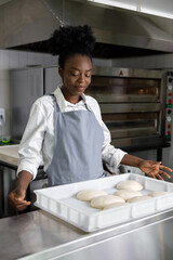 African american young woman baking pizza in pizzeria
