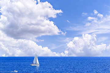 Boat, sailboat sailing on the beach of Mallorca under a blue sky with white clouds