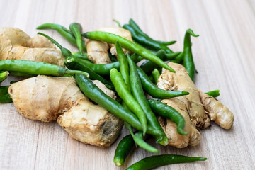 Fresh Ginger and green chili pepper on plain wooden table, green essential vegetables for all essential foods, view of unpeeled vegetables with plain background