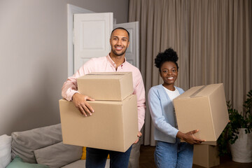 Man and woman relocating to a new house holding cardboard boxes with belongings