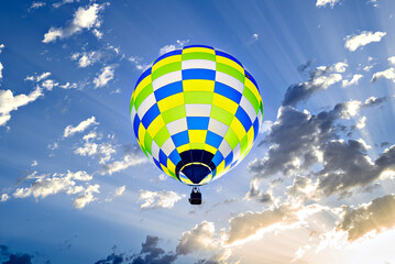 Colorful hot air balloon flying over blue sky with white clouds	