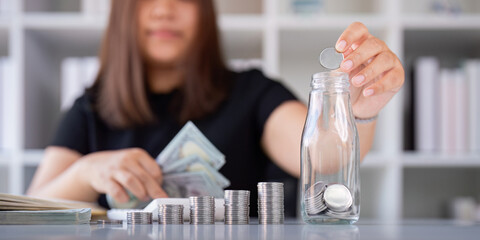 Woman saving money with hand putting coins in jug glass concept finance and accounting finance and...