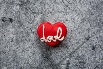 Homemade ginger cookies in the shape of a heart in red icing sugar. Delicious ginger cookies heart on a gray concrete background. Freshly baked gingerbread cookies for Valentine's Day.