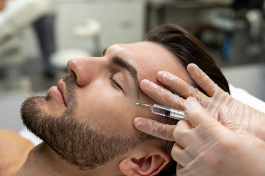 Dark-haired bearded man having session of mesotherapy in a beauty salon